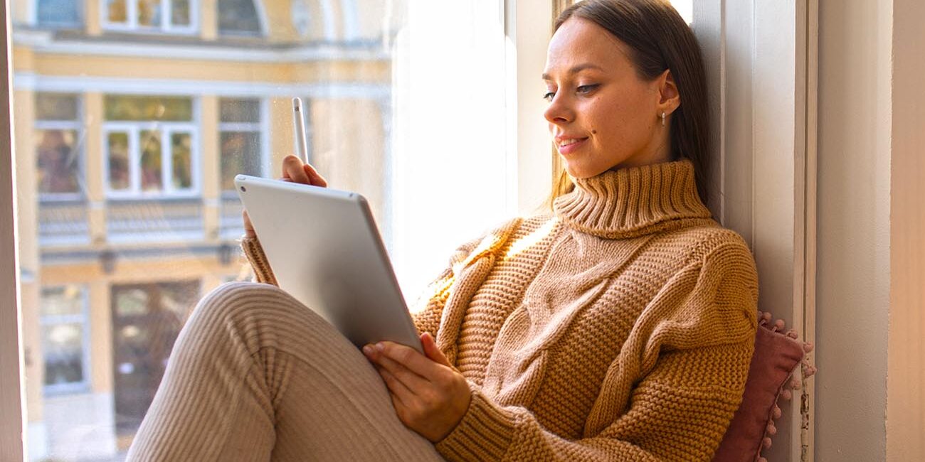 Moça lendo um livro na varanda.