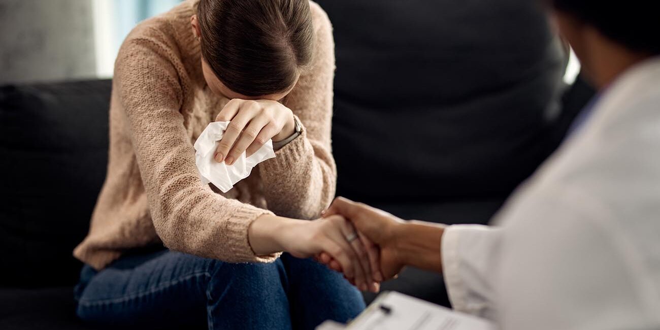 Mulher triste sendo consolada pelo terapeuta.