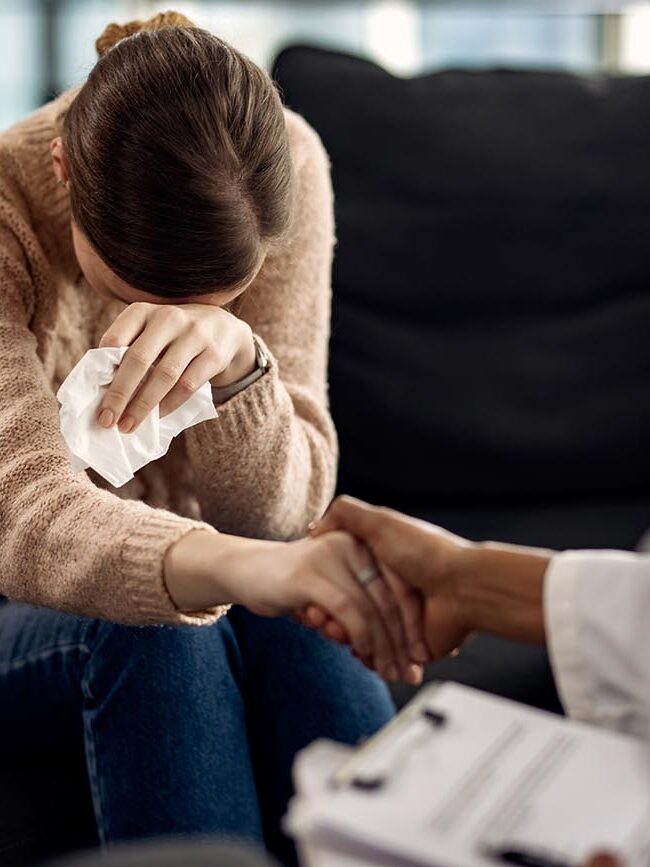 Mulher triste sendo consolada pelo terapeuta.
